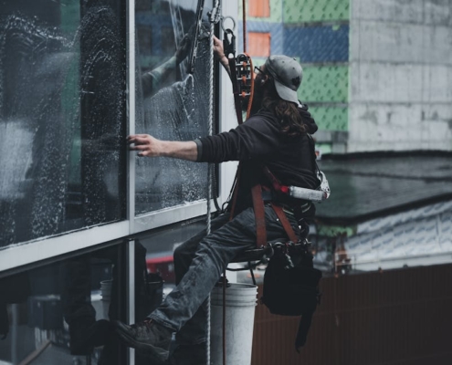 A man in a harness cleaning skyscraper windows with precision.