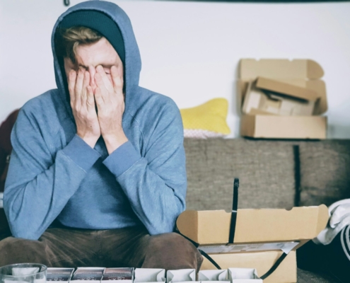 man covering face with both hands while sitting on bench