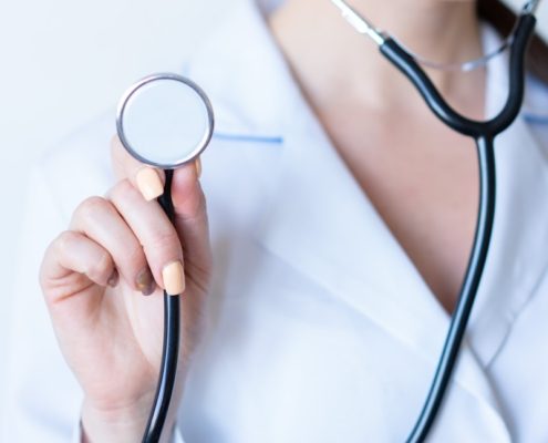 a woman in a white shirt holding a stethoscope