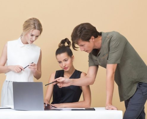 man teaching woman while pointing on gray laptop